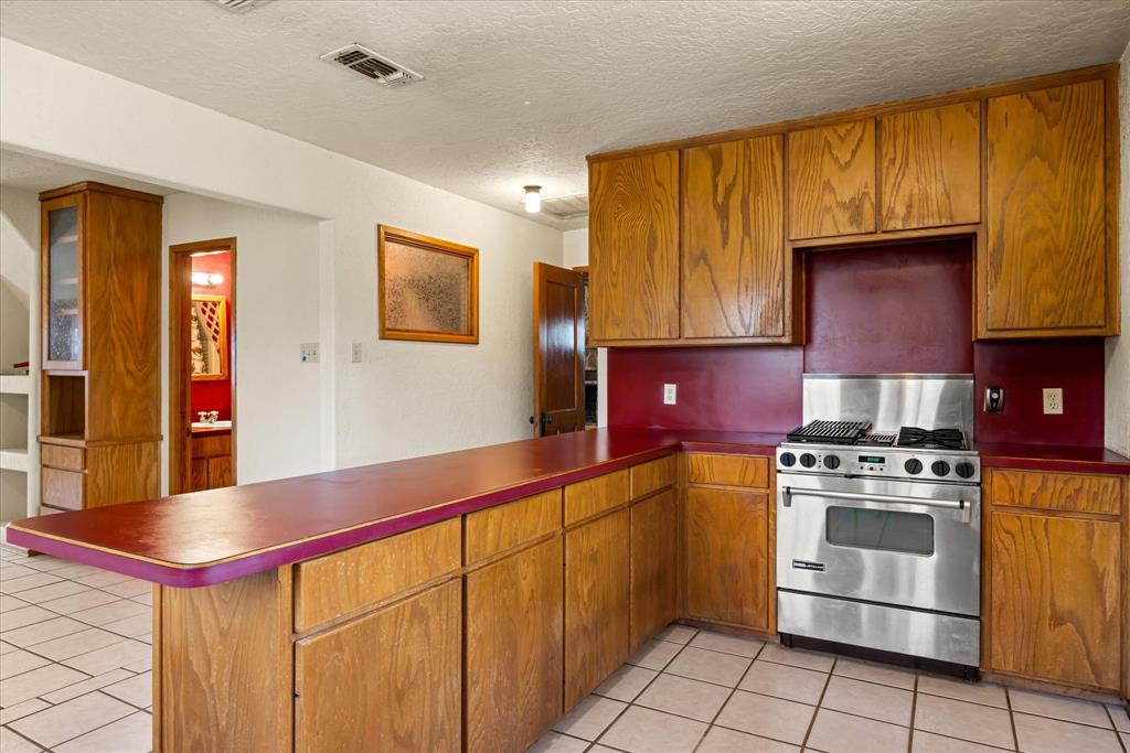 1601 Stafford Road Weatherford, TX 76088 - Photo 17 of 40 a kitchen with stainless steel appliances granite countertop a stove a sink and a microwave