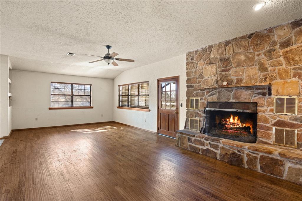 1601 Stafford Road Weatherford, TX 76088 - Photo 22 of 40 an empty room with windows fireplace and wooden floor