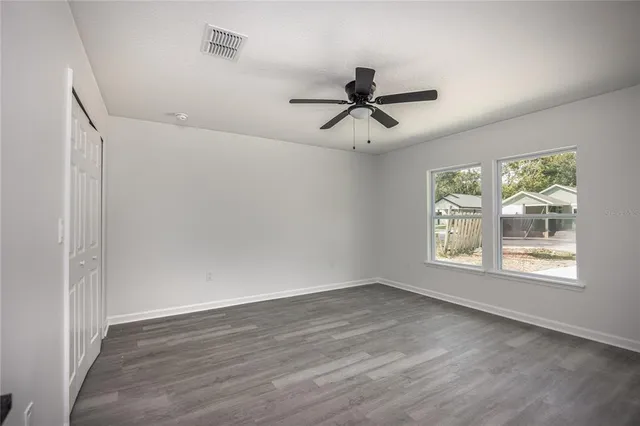 a view of empty room with wooden floor and fan