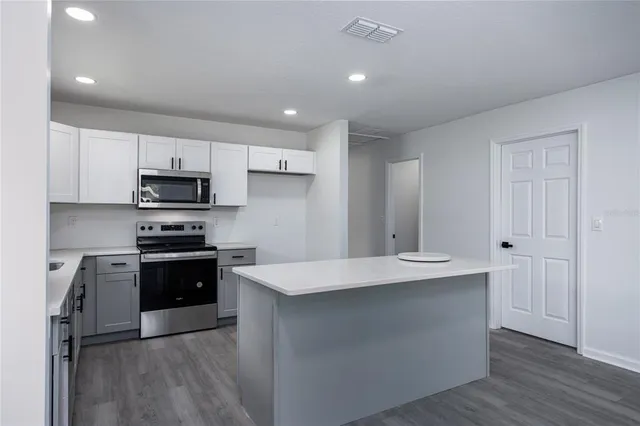 a large kitchen with stainless steel appliances granite countertop a stove a sink and a refrigerator