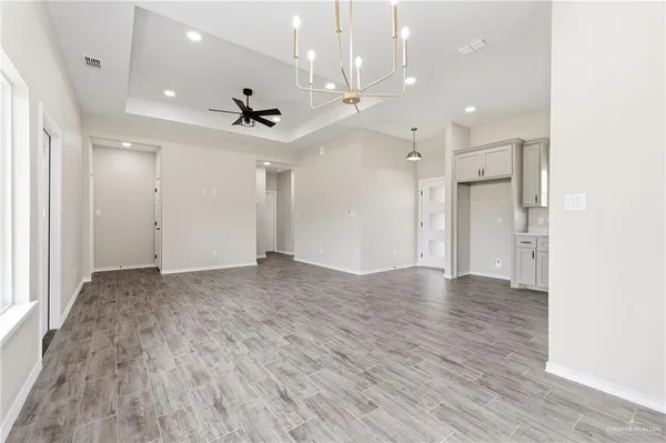 an empty room with wooden floor and a ceiling fan