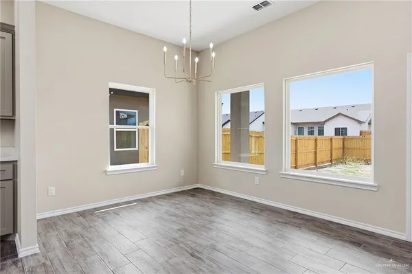 an empty room with wooden floor cabinet and windows