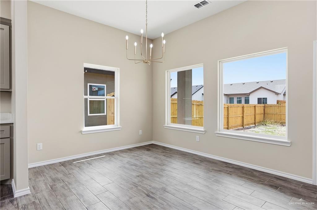 18032 Spruce Street Combes, TX 78552 - Photo 5 of 14 an empty room with wooden floor cabinet and windows