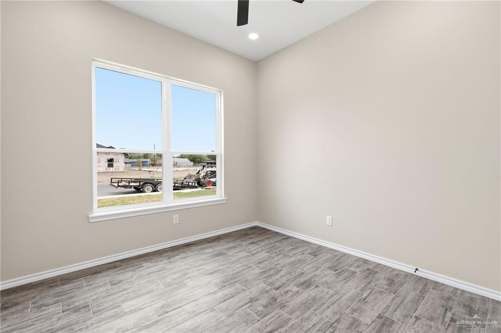 18032 Spruce Street Combes, TX 78552 - Photo 7 of 14 an empty room with wooden floor and windows