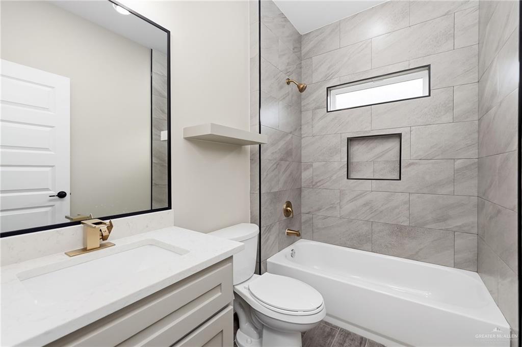 18032 Spruce Street Combes, TX 78552 - Photo 8 of 14 a bathroom with a granite countertop bathtub shower sink vanity mirror and toilet