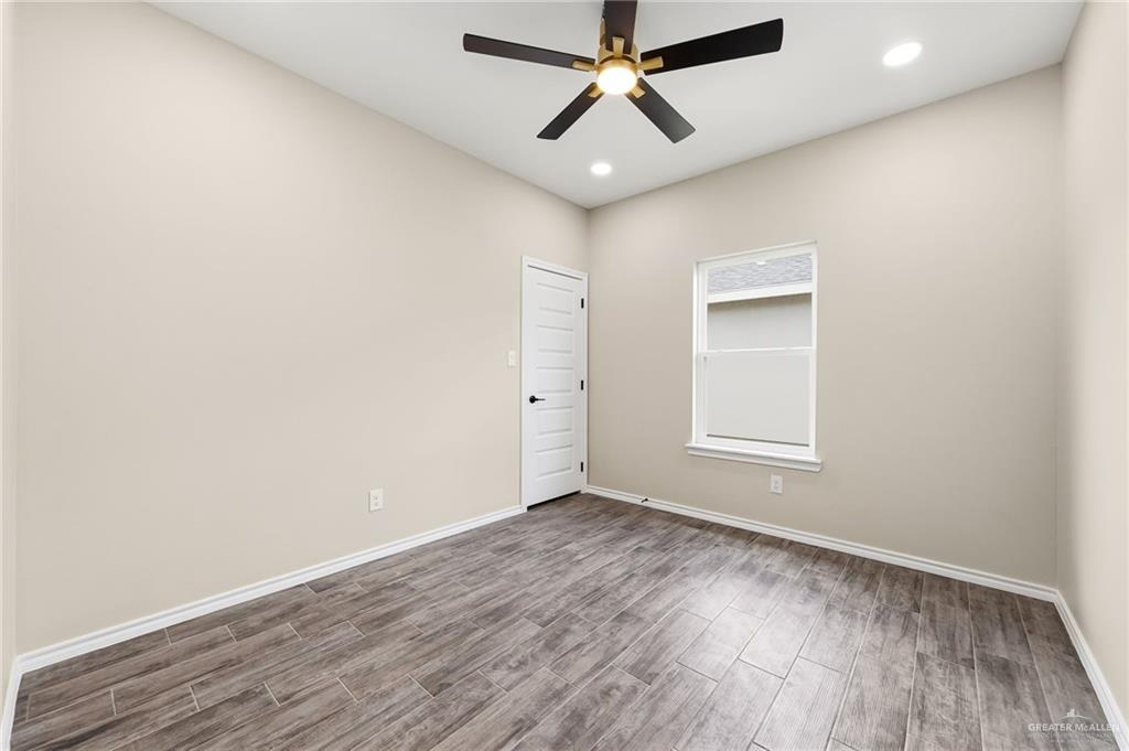 18032 Spruce Street Combes, TX 78552 - Photo 9 of 14 an empty room with wooden floor ceiling fan and windows
