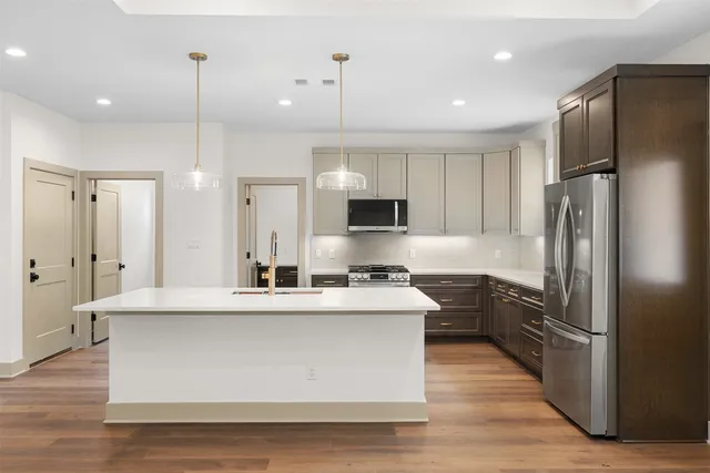 a large kitchen with stainless steel appliances kitchen island a large counter top and a refrigerator