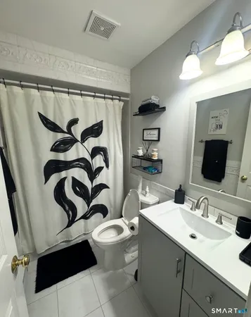 a bathroom with a sink a toilet a mirror and shower curtain