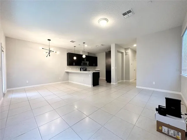 a view of a electric appliances in kitchen and empty room with wooden floor