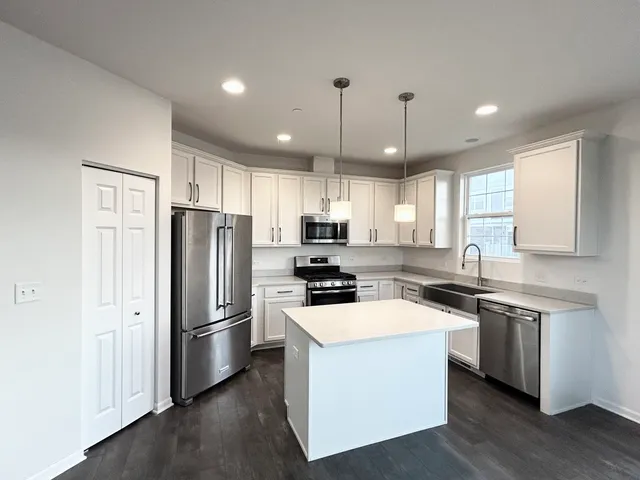 a kitchen with stainless steel appliances a stove a sink a refrigerator a center island and a window