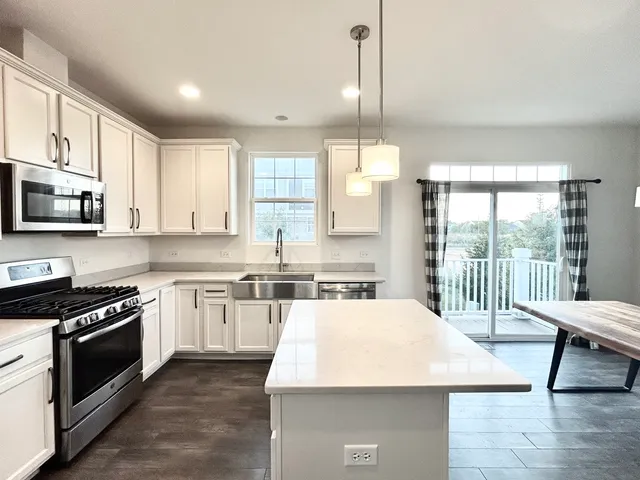 a large kitchen with stainless steel appliances granite countertop a stove a sink dishwasher a microwave oven with cabinets and wooden floor