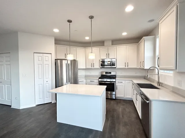 a kitchen with stainless steel appliances a stove a sink a refrigerator a center island and a window