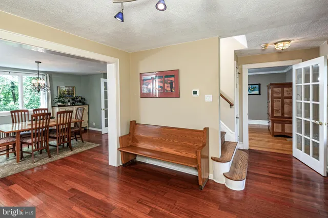 a dining room with wooden floor a chandelier a glass table and chairs
