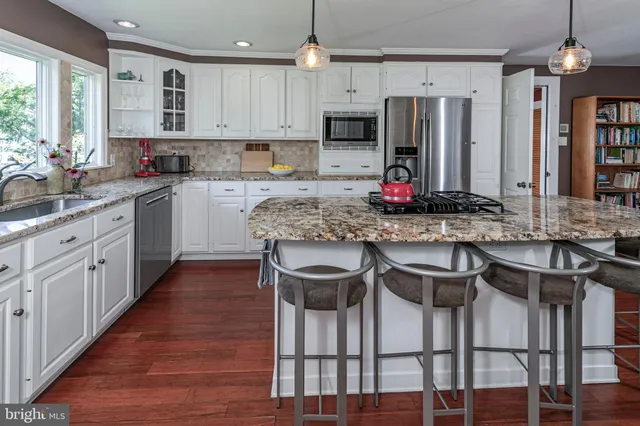 a kitchen with stainless steel appliances kitchen island granite countertop a sink stove and refrigerator