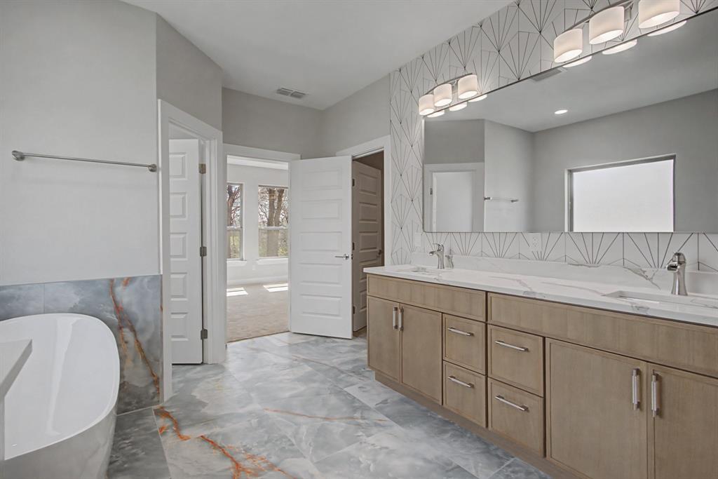 108 Winding Way Azle, TX 76020 - Photo 25 of 39 Bathroom featuring a freestanding tub, tile walls, double vanity, a wainscoted wall, and light marble finish floors