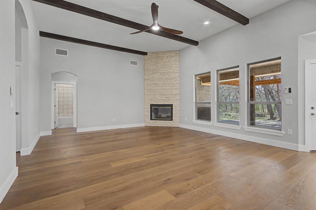 108 Winding Way Azle, TX 76020 - Photo 4 of 39 Unfurnished living room with arched walkways, a stone fireplace, dark wood-style floors, and ceiling fan