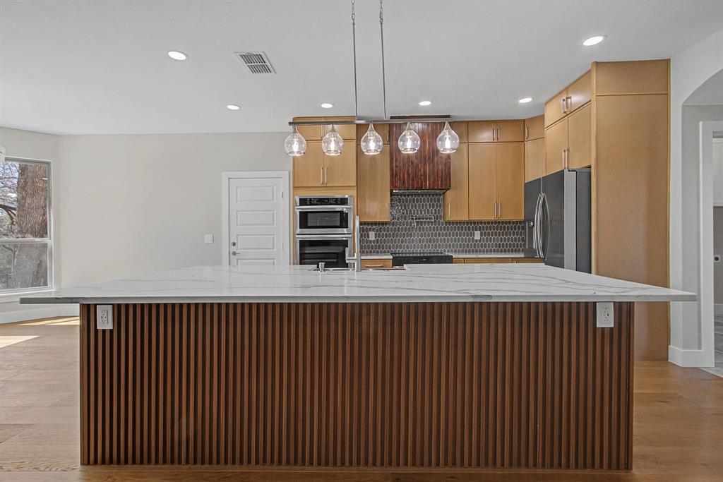 108 Winding Way Azle, TX 76020 - Photo 6 of 39 Kitchen featuring light stone counters, a spacious island, stainless steel appliances, light wood finished floors, and tasteful backsplash