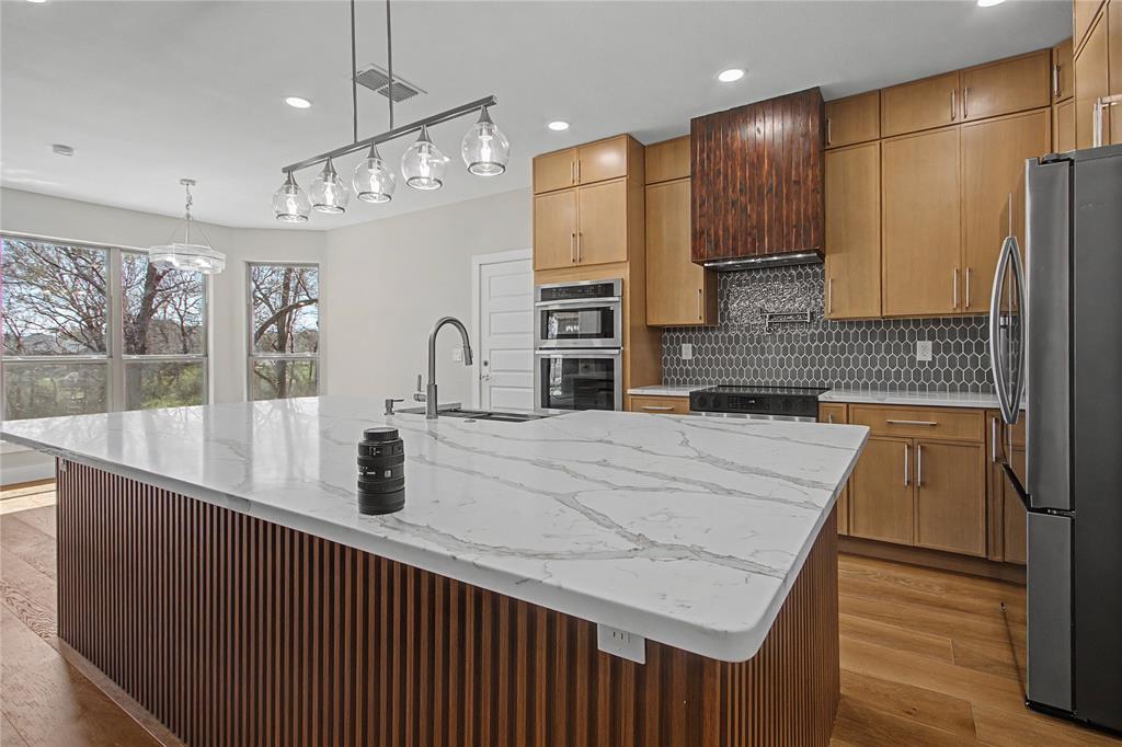 108 Winding Way Azle, TX 76020 - Photo 7 of 39 Kitchen with stainless steel appliances, light stone countertops, light wood finished floors, and a large island with sink