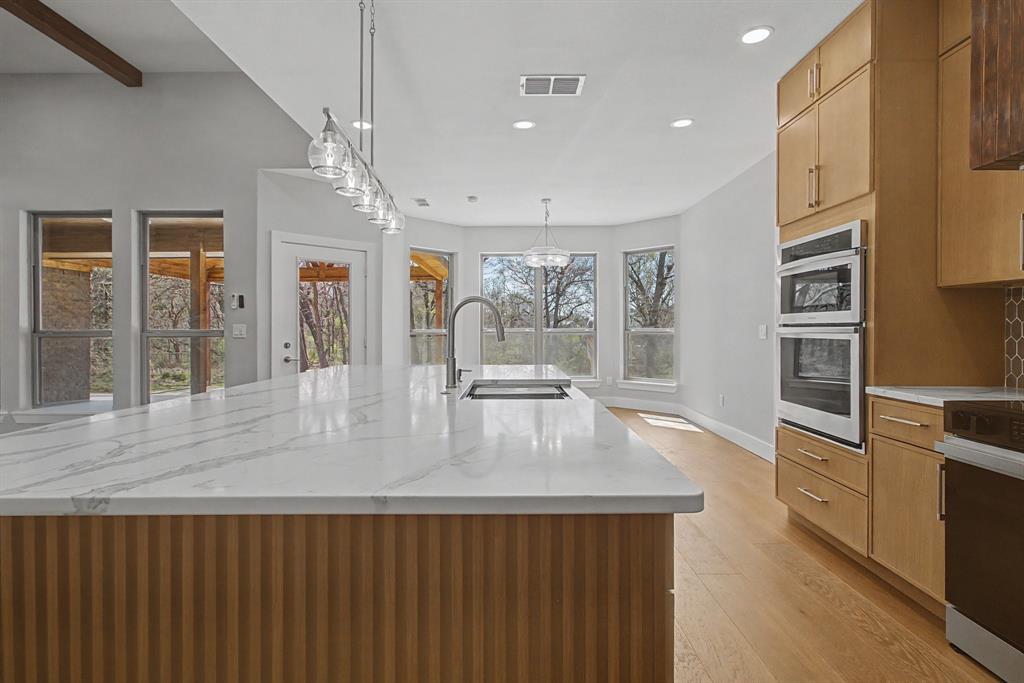 108 Winding Way Azle, TX 76020 - Photo 8 of 39 Kitchen with light stone counters, light wood-style flooring, a large island, hanging light fixtures, and stainless steel appliances