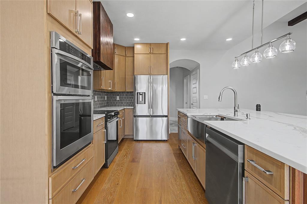 108 Winding Way Azle, TX 76020 - Photo 9 of 39 Kitchen with stainless steel appliances, arched walkways, light stone countertops, light wood-style flooring, and tasteful backsplash