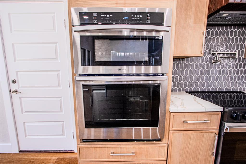 108 Winding Way Azle, TX 76020 - Photo 10 of 39 Kitchen with stainless steel appliances, extractor fan, light wood finish cabinets, light stone counters, and wood finished floors