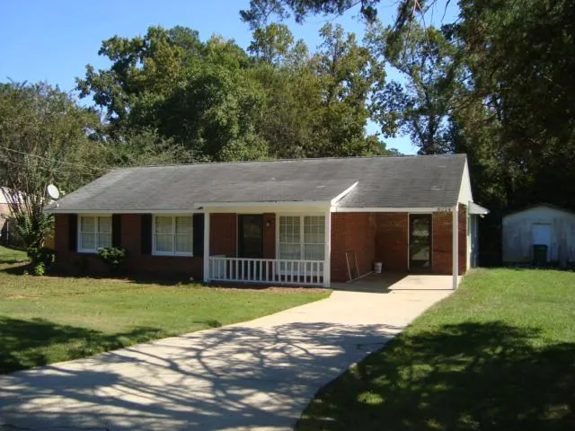 a front view of house with yard and trees in the background