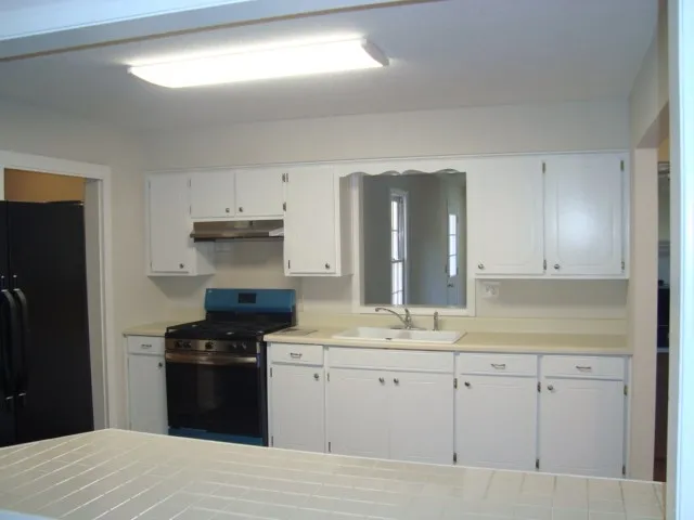 a kitchen with a sink dishwasher and a stove with wooden floor