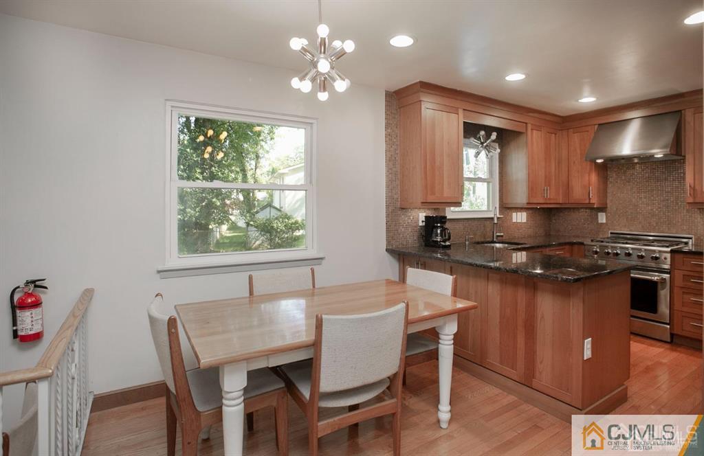 7 Douglas Drive Edison, NJ 08817 - Photo 9 of 26 a kitchen with granite countertop a stove a sink a dining table and chairs