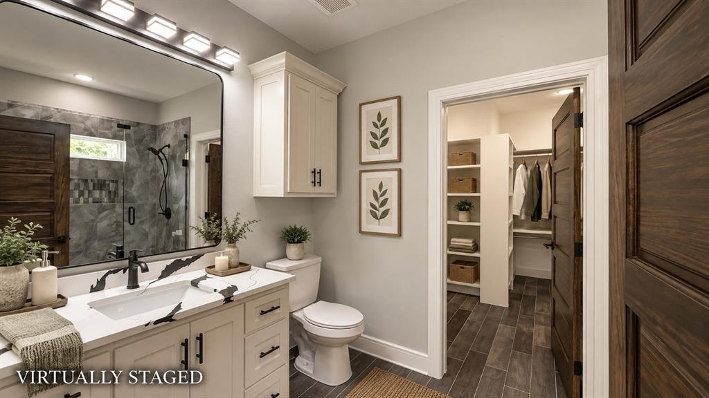 302-304 West Pine Street Whitewright, TX 75491 - Photo 27 of 38 Bathroom featuring a vanity with a white countertop, dark wood-finish flooring, a glass-enclosed shower, and built-in closet shelving