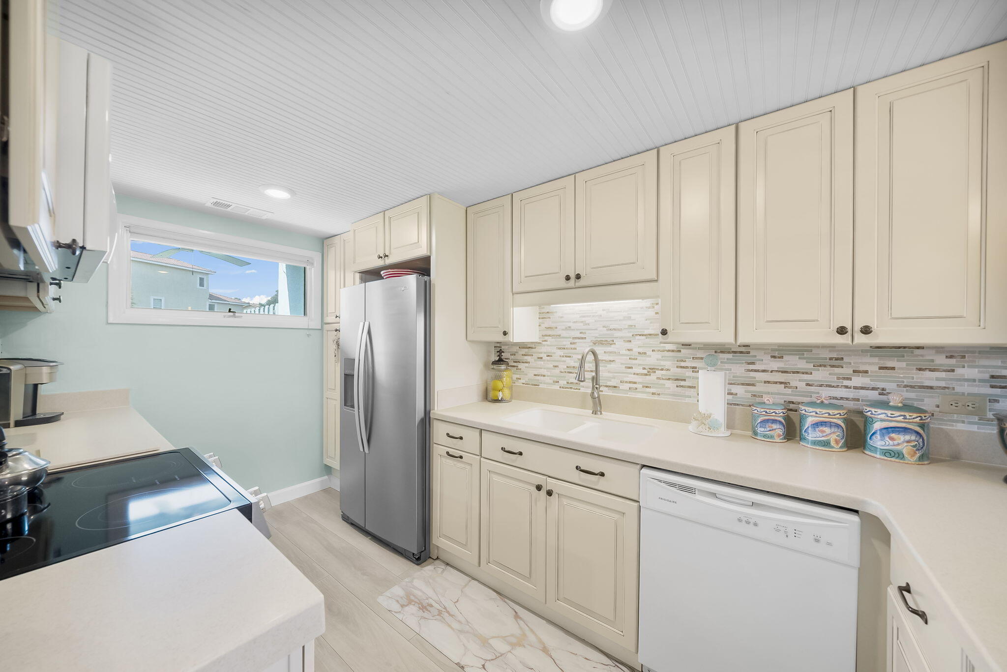 22400 Front Beach Road, Unit 24 Panama City Beach, FL 32413 - Photo 10 of 41 a kitchen with stainless steel appliances white cabinets and a refrigerator