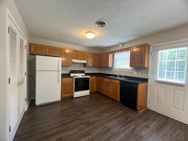 a kitchen with granite countertop a refrigerator and wooden floors