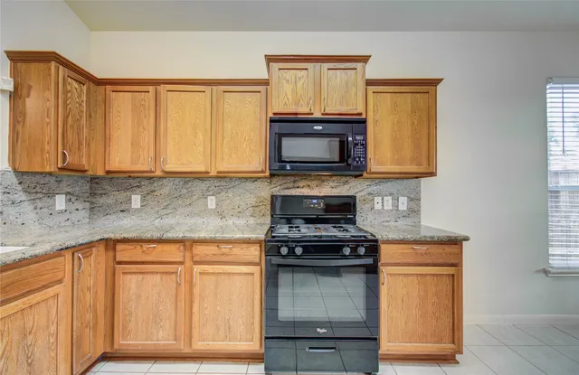 a kitchen with granite countertop cabinets stainless steel appliances and a window