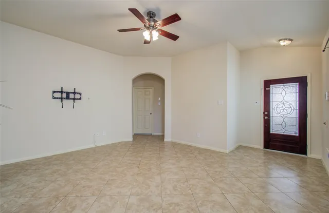 an empty room with chandelier fan and windows