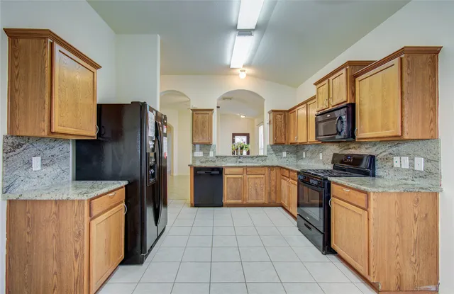 a large kitchen with stainless steel appliances granite countertop a refrigerator and a stove top oven