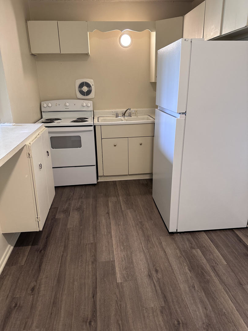 a kitchen with a refrigerator a sink and wooden floor