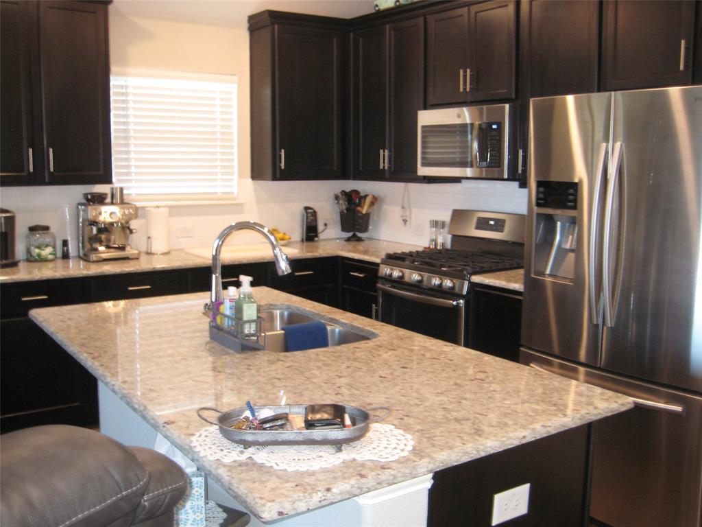 2 Grouse Run Sanger, TX 76266 - Photo 6 of 26 a kitchen with granite countertop a sink a stove and refrigerator