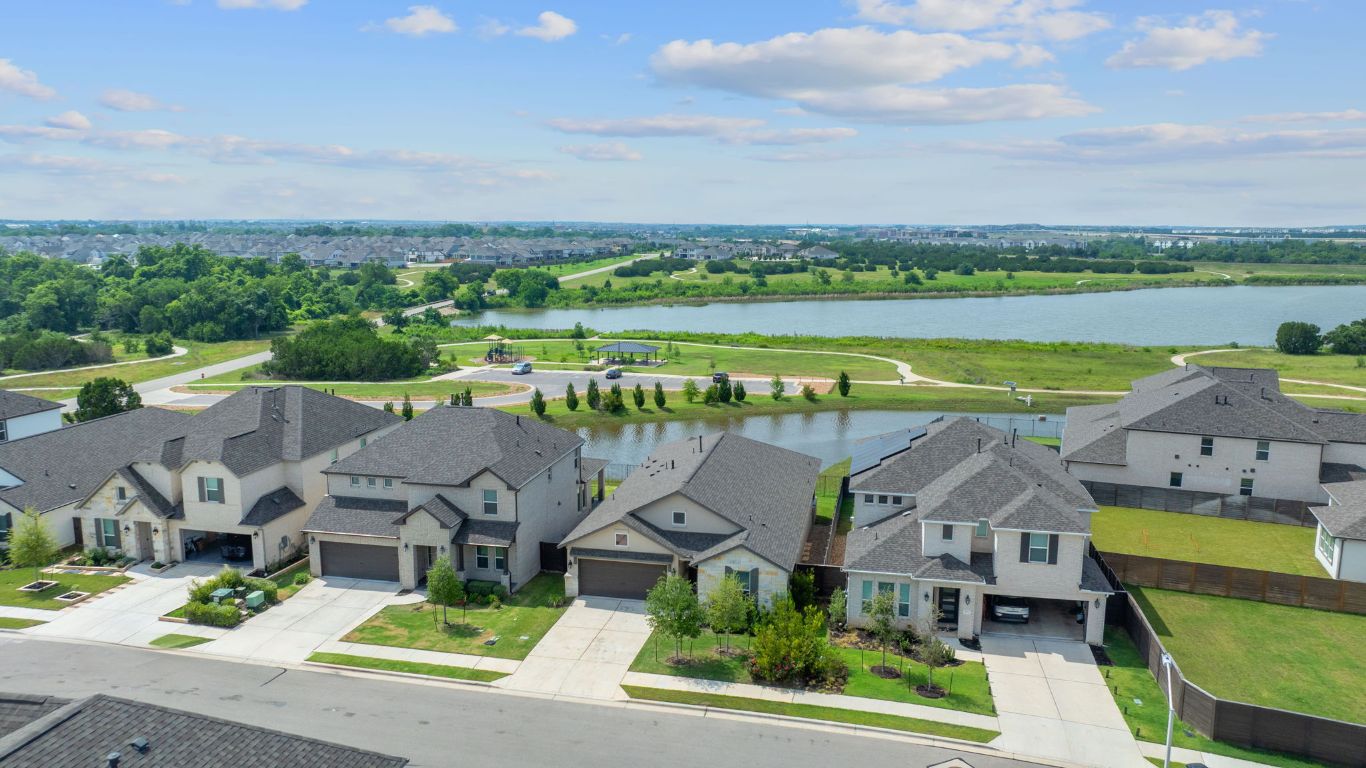 an aerial view of residential houses with outdoor space and lake view