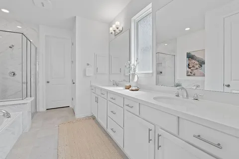 a spacious bathroom with double sink a toilet a shower and a mirror