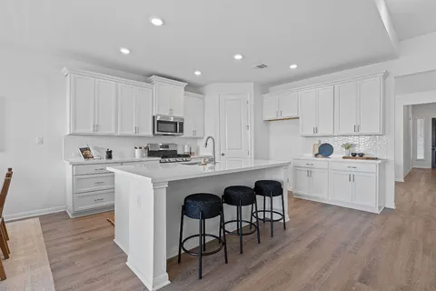 a kitchen with granite countertop white cabinets a sink dishwasher and a stove with wooden floor