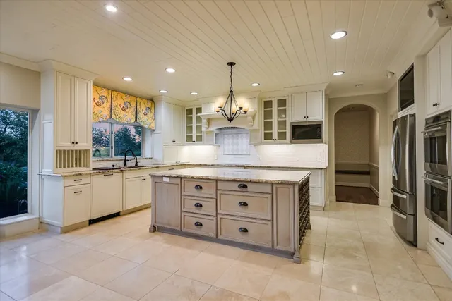 a large kitchen with kitchen island a large counter top stainless steel appliances and cabinets