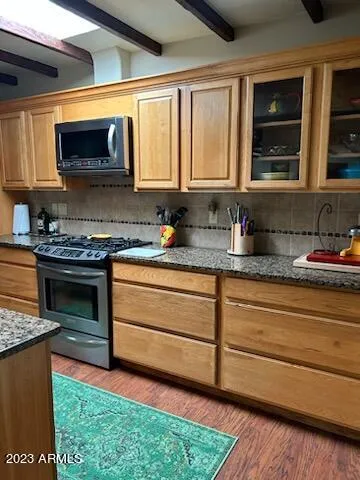 a kitchen with granite countertop stainless steel appliances a stove sink and microwave