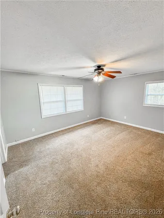 an empty room with windows and ceiling fan view