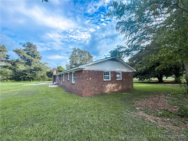 a view of house with yard and trees in the background