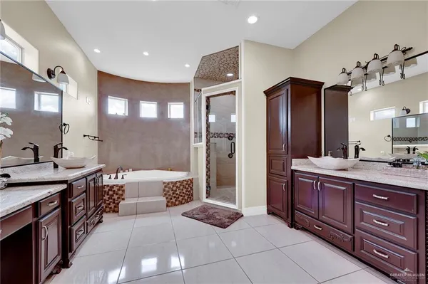 a spacious en suite bathroom with a granite countertop sink mirror and shower