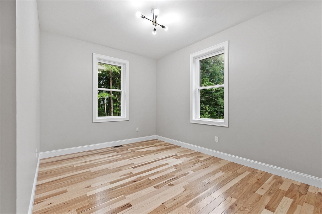 186 Justice Hill Road, Unit OAKMONT Sterling, MA 01564 - Photo 15 of 34 a view of an empty room with wooden floor and a window