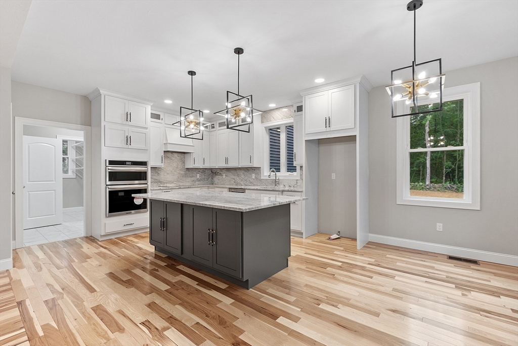 186 Justice Hill Road, Unit OAKMONT Sterling, MA 01564 - Photo 6 of 34 a large kitchen with kitchen island white cabinets and stainless steel appliances