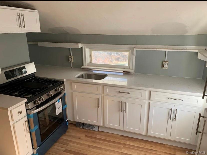 331 Angola Road, Unit 7 Cornwall, NY 12518 - Photo 3 of 7 Compact kitchen featuring white shaker-style cabinetry, a stainless steel gas range, a stainless steel sink, light-toned countertops, and wood-finish flooring