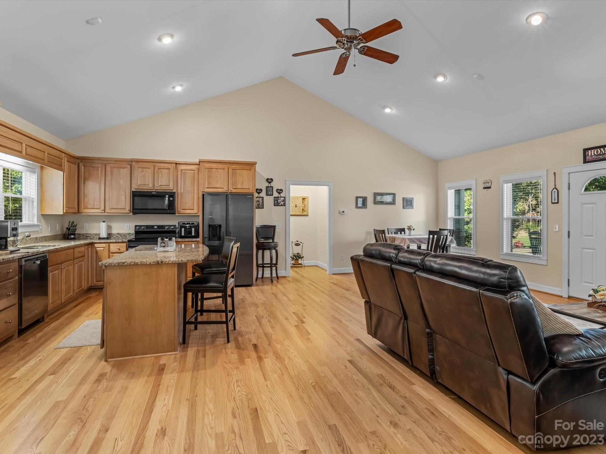 125 Boulder Ridge Drive State Road, NC 28676 - Photo 7 of 39 a kitchen with stainless steel appliances granite countertop a refrigerator a stove top oven a sink dishwasher and a dining table with wooden floor