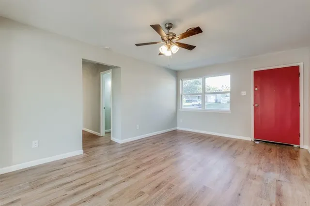 an empty room with wooden floor fan and windows