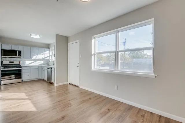 a view of a kitchen with wooden floor electronic appliances and windows